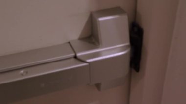 Yangın çıkışı kapısı. Adam merdiven koridorunun yangın kapısını açtı. Yangın çıkan binadan acil çıkış. Kalın metal malzemeden yapılmış bir kapı. Yangını korumak için güvenlik için alarmlı..