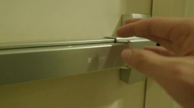 Yangın çıkışı kapısı. Adam merdiven koridorunun yangın kapısını açtı. Yangın çıkan binadan acil çıkış. Kalın metal malzemeden yapılmış bir kapı. Yangını korumak için güvenlik için alarmlı..