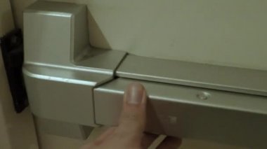 Yangın çıkışı kapısı. Adam merdiven koridorunun yangın kapısını açtı. Yangın çıkan binadan acil çıkış. Kalın metal malzemeden yapılmış bir kapı. Yangını korumak için güvenlik için alarmlı..