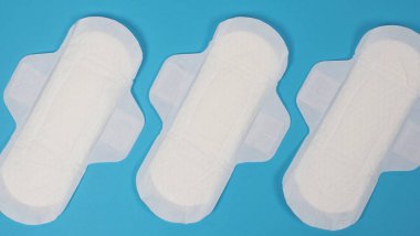 Mavi arka planda kadın hijyenik peçeteleri. Üst Manzara. Adet kanlarını emmek için kadınlar tarafından takılan emme pedleri. Açık mavi kağıda düzenlenmiş konforlu beyaz hijyenik peçeteler. Hijyen kavramını temsil et