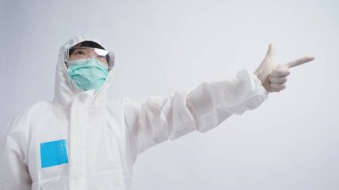 PPE takımındaki doktor beyaz lastik eldivenler ve temiz gözlükler takıyor ve yeşil N95 yüz maskesi salgın Coronavirus 'u koruyor. El işareti yap. Virüsü yenen zaferi temsil ediyor. İzole edilmiş.
