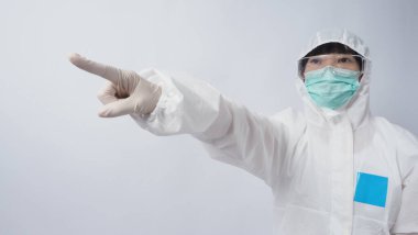 PPE takımındaki doktor beyaz lastik eldivenler ve temiz gözlükler takıyor ve yeşil N95 yüz maskesi salgın Coronavirus 'u koruyor. El işareti yap. Virüsü yenen zaferi temsil ediyor. İzole edilmiş.