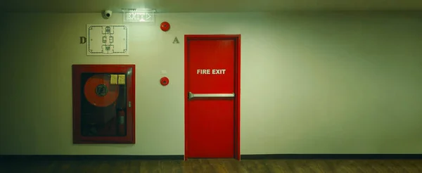 Fire exit door. Fire exit emergency door red color metal material with alarm and emergency light and fire extinguish equipment on building wall for safety protection. Doors for escape conflagration.