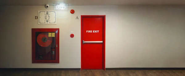 Fire exit door. Fire exit emergency door red color metal material with alarm and emergency light and fire extinguish equipment on building wall for safety protection. Doors for escape conflagration.