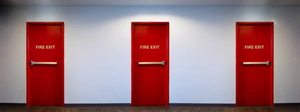 Fire exit door. Fire exit emergency door red color metal material with alarm and emergency light and fire extinguish equipment on building wall for safety protection. Doors for escape conflagration.