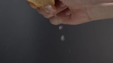 Siyah arka planda limonun yarısını sıkmak. Misket limonlu limon. Stüdyo 4K video kaydında limon suyunu sıkıştırıp ezmek. Ekşi ve ferahlatıcı içecek menüsünü temsil et.