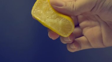 Siyah arka planda limonun yarısını sıkmak. Misket limonlu limon. Stüdyo 4K video kaydında limon suyunu sıkıştırıp ezmek. Ekşi ve ferahlatıcı içecek menüsünü temsil et.
