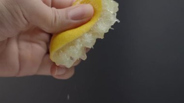 Siyah arka planda limonun yarısını sıkmak. Misket limonlu limon. Stüdyo 4K video kaydında limon suyunu sıkıştırıp ezmek. Ekşi ve ferahlatıcı içecek menüsünü temsil et.