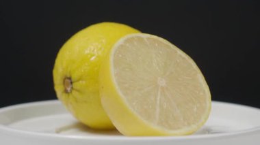 Lezzetli limon pikapta hareket ediyor. Lezzetli limonlar siyah arka planda izole edilir. Tam ve yarım sarı limon koyu arka planda izole edilir. Kapat. Ekşi ve ferahlatıcı içecek menüsünü temsil et.