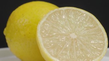 Lezzetli limon pikapta hareket ediyor. Lezzetli limonlar siyah arka planda izole edilir. Tam ve yarım sarı limon koyu arka planda izole edilir. Kapat. Ekşi ve ferahlatıcı içecek menüsünü temsil et.