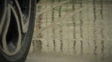 Yağmur damlaları ve yağmur suyunda araba lastikleri. Yağmurda araba park etmek. Yağmur mevsimi ve ıslak kaldırımda lastikler. Islak bir yolda araba lastiği ya da tekerlekleri kapatın. Yağmur mevsimi kavramında otomatiği temsil et.