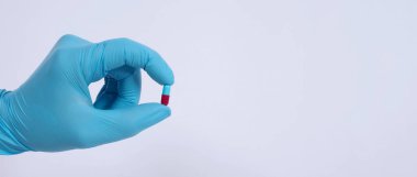 Taking or holding medication pills in hand. Capsule pill on white background isolated. Nitrile disposable gloves and medicines. Drugs healthcare treatment and supplement relieve symptoms of COVID 19.