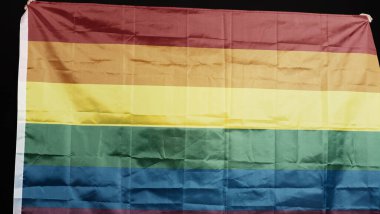 Siyah arka planda LGBTQ gurur bayrağı. Lgbt gökkuşağı bayrağı eşcinsellerin elinde. Özgürlüğün, barışın, eşitliğin, sevginin ve cinselliğin çeşitliliğinin sembolü. Lezbiyen Gay Biseksüel Cinsiyet Değiştiren Queer.