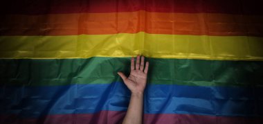 Siyah arka planda LGBTQ gurur bayrağı. Lgbt gökkuşağı bayrağı eşcinsellerin elinde. Özgürlüğün, barışın, eşitliğin, sevginin ve cinselliğin çeşitliliğinin sembolü. Lezbiyen Gay Biseksüel Cinsiyet Değiştiren Queer.