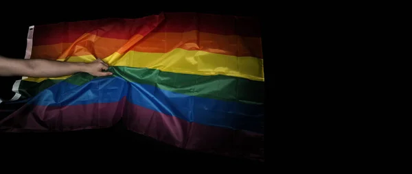 LGBTQ pride flag on black background. Lgbt rainbow flag in gay hand. Represent symbol of freedom peace equality and love and respect  diversity of sexuality. Lesbian Gay Bi sexsual Transgender Queer.