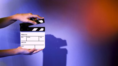 Film alkışlama tahtası. Ekip el kameraya karşı plastik ve ahşap film tahtası tutuyor. Video yapımında ve film stüdyosunda kullanılan alkışlar film endüstrisinde işe yarıyor. Mürettebatın elinde film tahtası.