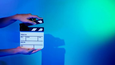 Film alkışlama tahtası. Ekip el kameraya karşı plastik ve ahşap film tahtası tutuyor. Video yapımında ve film stüdyosunda kullanılan alkışlar film endüstrisinde işe yarıyor. Mürettebatın elinde film tahtası.