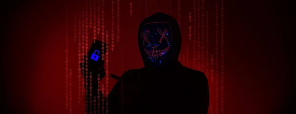 Digital security Concept. Anonymous hacker with mask holding smartphone hacked. Personal and Cyber data security in mobile phone stolen by man in mask. Represent digital privacy protection concept.