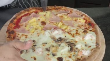 Pizza homemade from brick oven or stone stove. Traditional Italian pizza cooked in heat fired oven. After that cut by circle knife before serving. Fresh Homemade Pizza. Half Seafood and half Hawaiian.