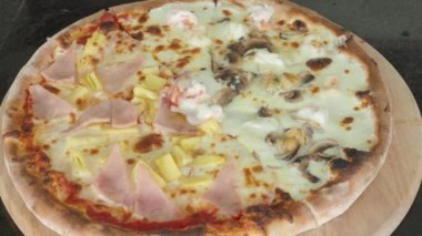 Pizza homemade from brick oven or stone stove. Traditional Italian pizza cooked in heat fired oven. After that cut by circle knife before serving. Fresh Homemade Pizza. Half Seafood and half Hawaiian.