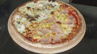Pizza homemade from brick oven or stone stove. Traditional Italian pizza cooked in heat fired oven. After that cut by circle knife before serving. Fresh Homemade Pizza. Half Seafood and half Hawaiian.