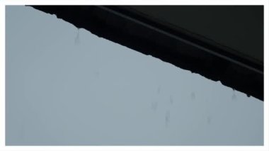 Yağmur ve çatı. Çatıdan yağan yağmur. Damlalar çatıdan aşağı akıyor. Yağmurlu gökyüzünde yağmur damlası damlıyor. Hava tahmini. Tembelliği temsil et ve rahatla ya da sakin ol..