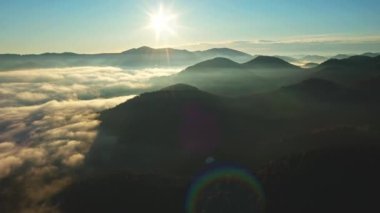Kırsalın güzel sonbahar tepelerinde uçuyor ve parlak sabah ışığıyla parlayan renkli dağların üzerinde. Renkli bir sonbahar sezonunun havadan görüntüsü. Karpat Dağları, Ukrayna.
