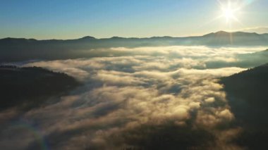 Kırsalın güzel sonbahar tepelerinde uçuyor ve parlak sabah ışığıyla parlayan renkli dağların üzerinde. Renkli bir sonbahar sezonunun havadan görüntüsü. Karpat Dağları, Ukrayna.