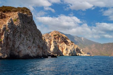 Denizde kayalar. Deniz manzarası, deniz dalgaları kayalara çarpıyor. Deniz dalgası taş kayaya çarpar. Denizde bir karabatak sürüsü.