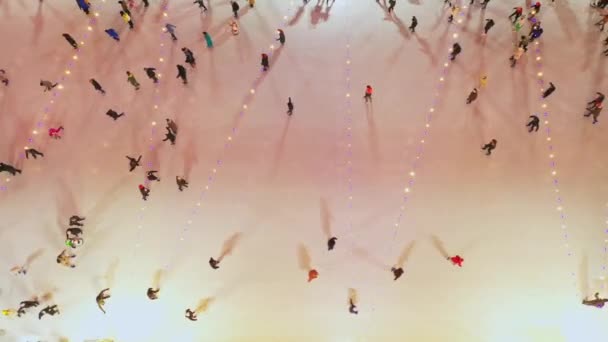 People ice skating on a large ice rink , aerial top down view from high angle — Stockvideo