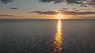 Okyanus suyunun üzerinde tropik altın gün batımı yavaş çekim hava manzarası. Güneş deniz manzarasına yansıyor. Sea Bay 'de kimsenin olmadığı bir kumsal. Güneşli bir akşamda sakin bir su manzarası. Yaz tatili. Tropik tatil