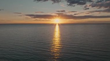 Okyanus suyunun üzerinde tropik altın gün batımı yavaş çekim hava manzarası. Güneş deniz manzarasına yansıyor. Sea Bay 'de kimsenin olmadığı bir kumsal. Güneşli bir akşamda sakin bir su manzarası. Yaz tatili. Tropik tatil