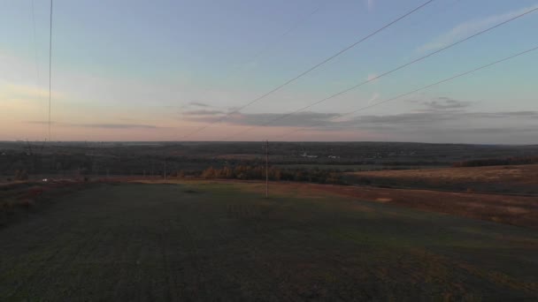 Drone aéreo filmando sob postes elétricos ao pôr do sol — Vídeo de Stock