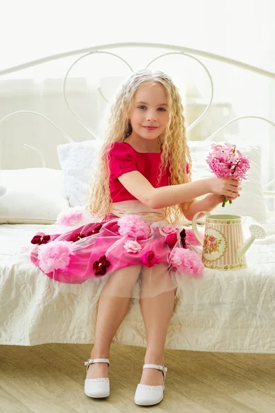 Pequena menina bonita em vestido rosa com flores em seu quarto — Fotografia de Stock