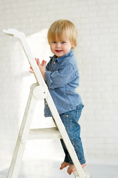 Smiling little boy standing on the step of a ladder — Stock Photo, Image