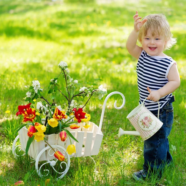Cheerful boy with watering can and flowers — Stock Photo, Image