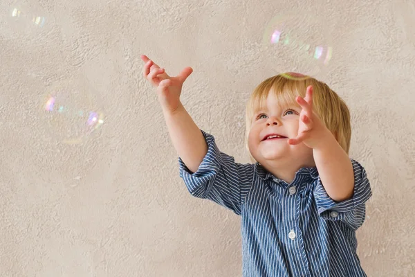 Позитивный ребенок ловит мыльные пузыри — стоковое фото