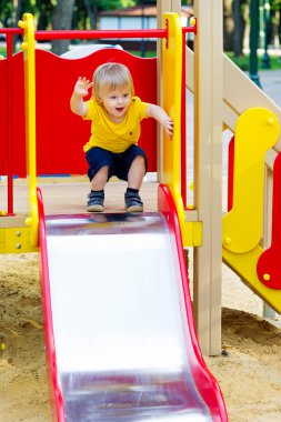 Adorable kid on the playground slide clipart