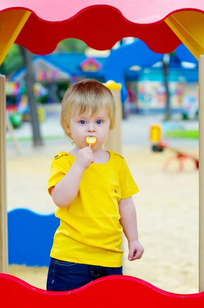 Gyerek eszik nyalóka a játszótéren — Stock Fotó