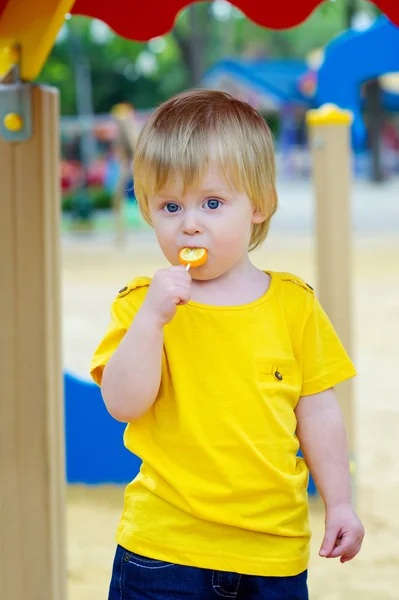 Dziecko jedzenie lolly pop na placu zabaw — Zdjęcie stockowe