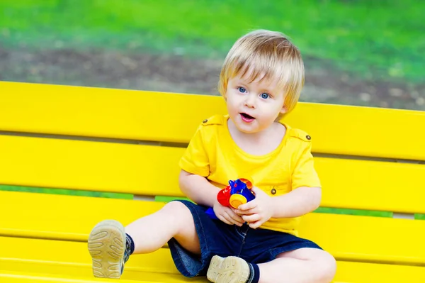 Kleinkind auf der gelben Bank — Stockfoto