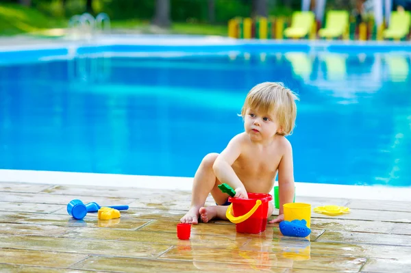 Toddler by the pool with toy bucket set — Stock Photo, Image