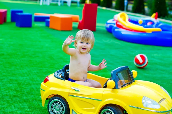 Ребенок в желтой машине на детской площадке — стоковое фото