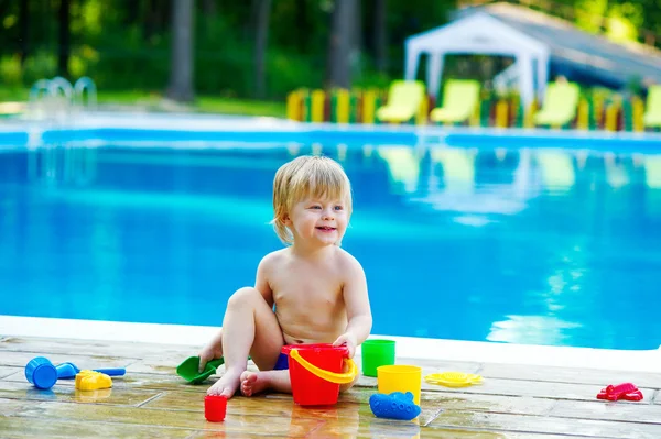 Criança à beira da piscina pálido com conjunto de balde de brinquedo — Fotografia de Stock