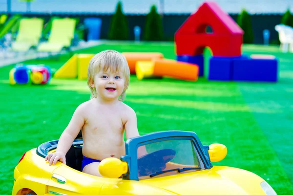 Ребенок в желтой машине на детской площадке — стоковое фото