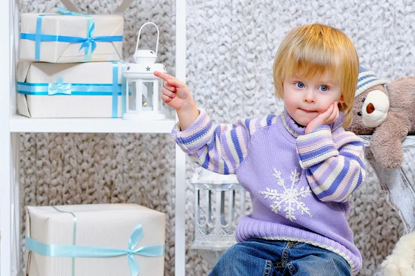 Cute little boy pointing at gift boxes — Stock Photo, Image