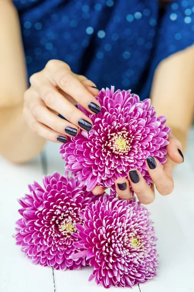 Hände mit Maniküre und rosa Blume — Stockfoto