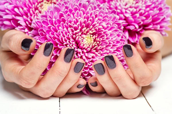 Mãos com manicure e flor rosa — Fotografia de Stock