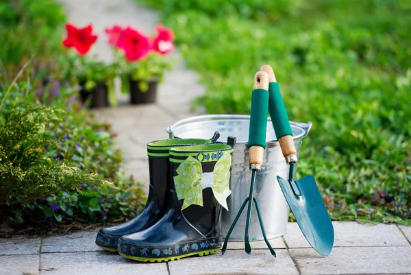 Små regn stövlar och trädgårdsredskap — Stockfoto