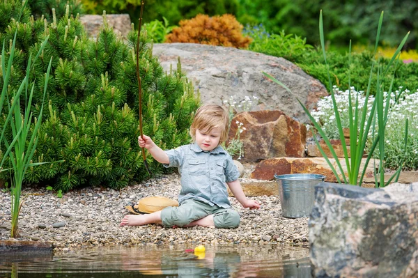 Piccolo ragazzo occupato la cattura di pesci nello stagno — Foto Stock